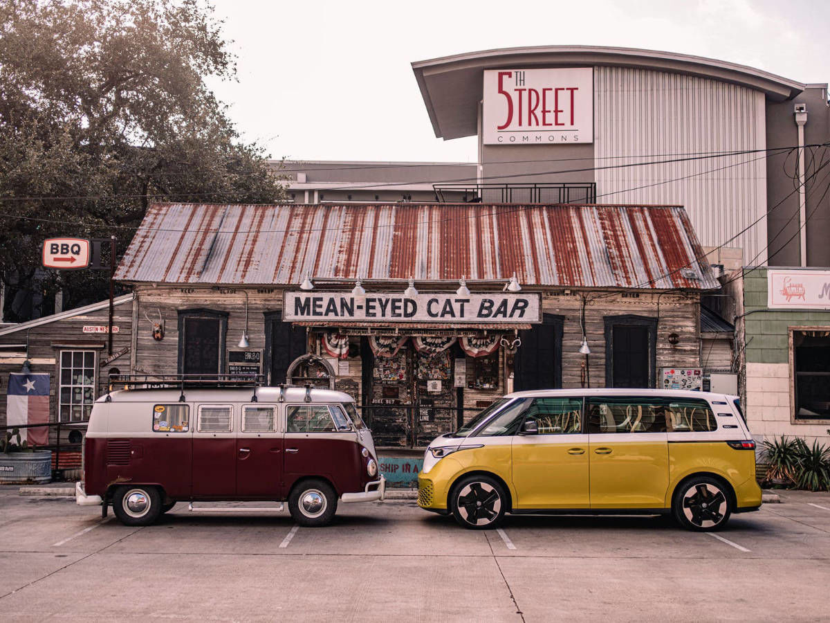 deux VW Westfalia de différentes époques face à face devant un vieux restaurant