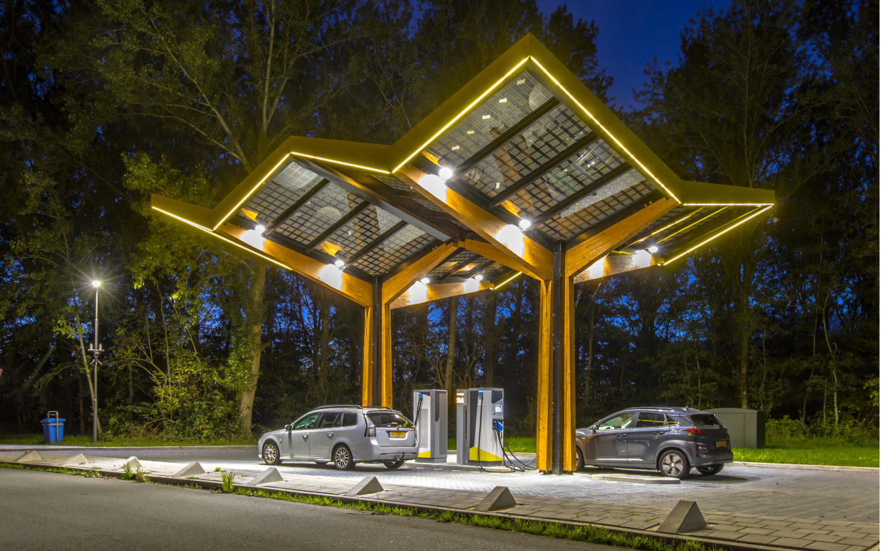 lit up charging station at night being used by a few vehicles