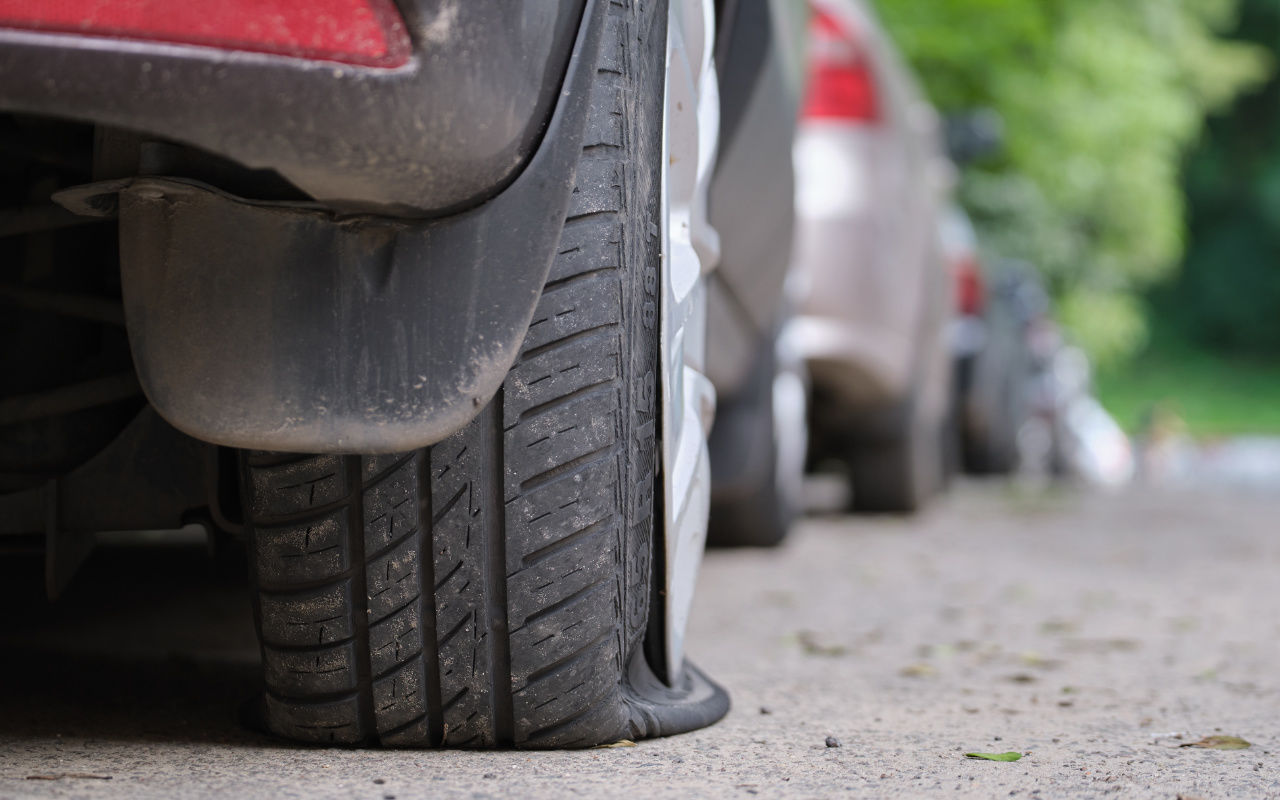 close up view of a car with a flat tire on the side of the road