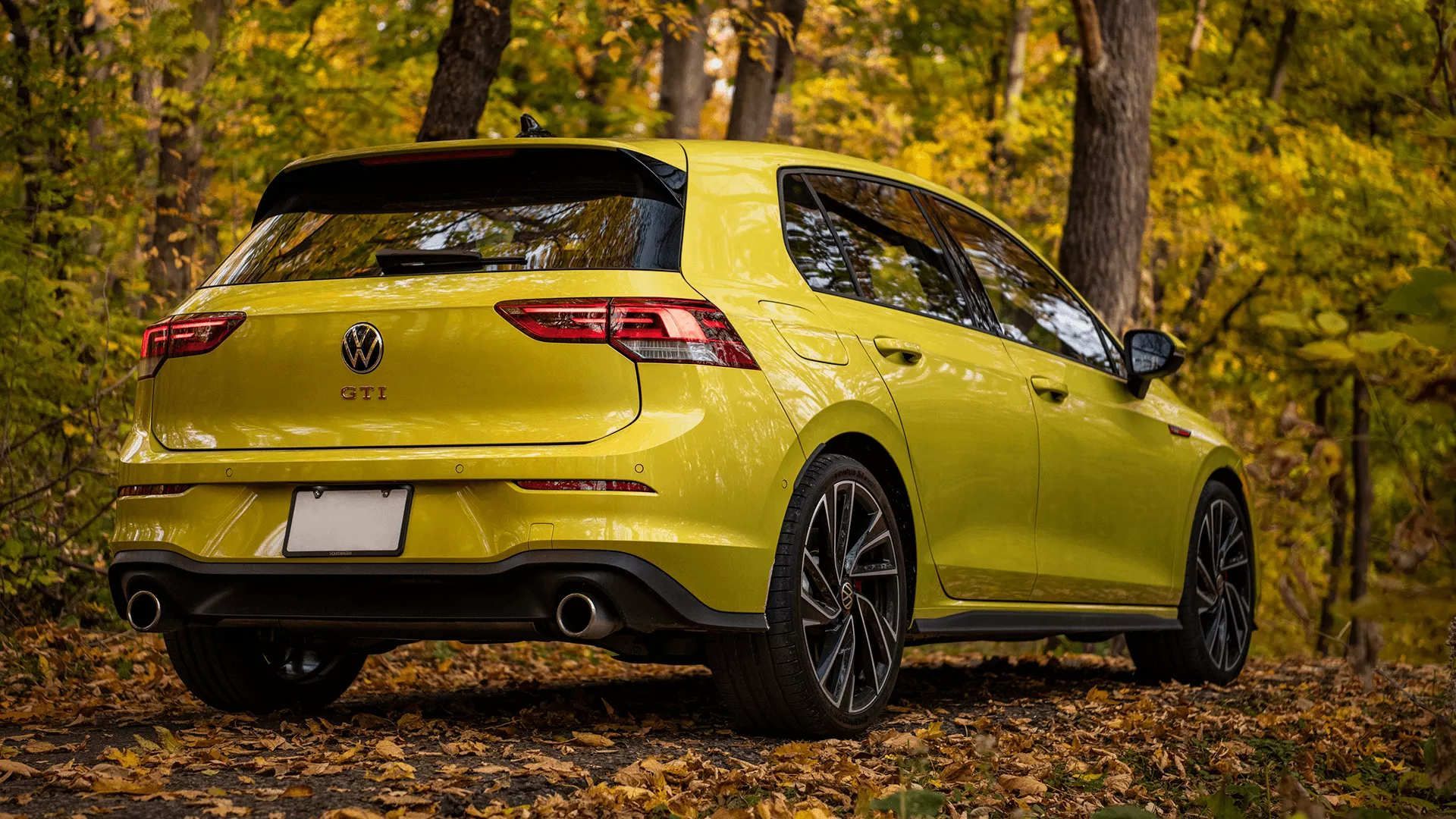 rear side view of a 2024 VW Golf GTI in an autumn forest