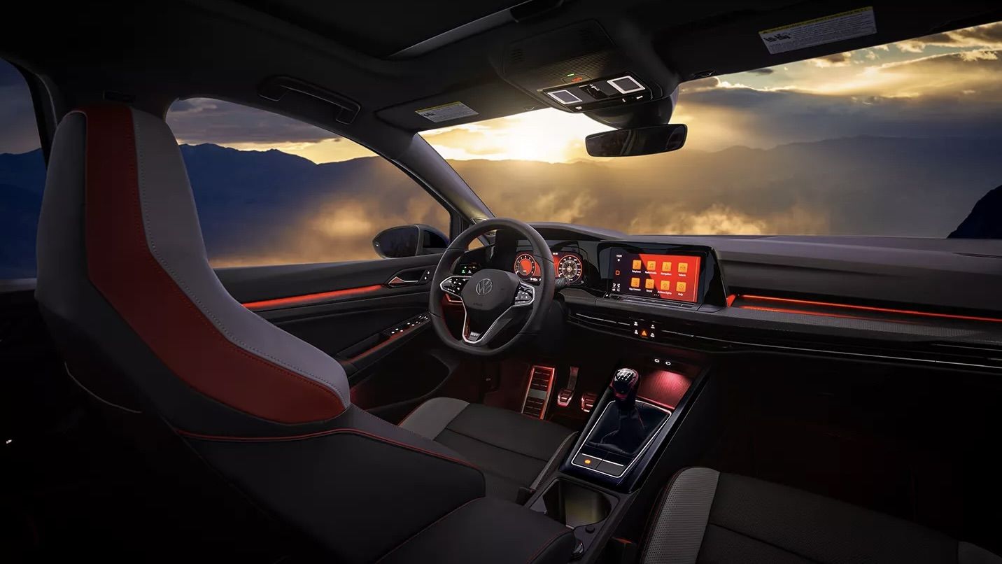 Intérieur de la Volkswagen Golf GTI 2024 avec un magnifique couché de soleil vue du haut d'une montagne.