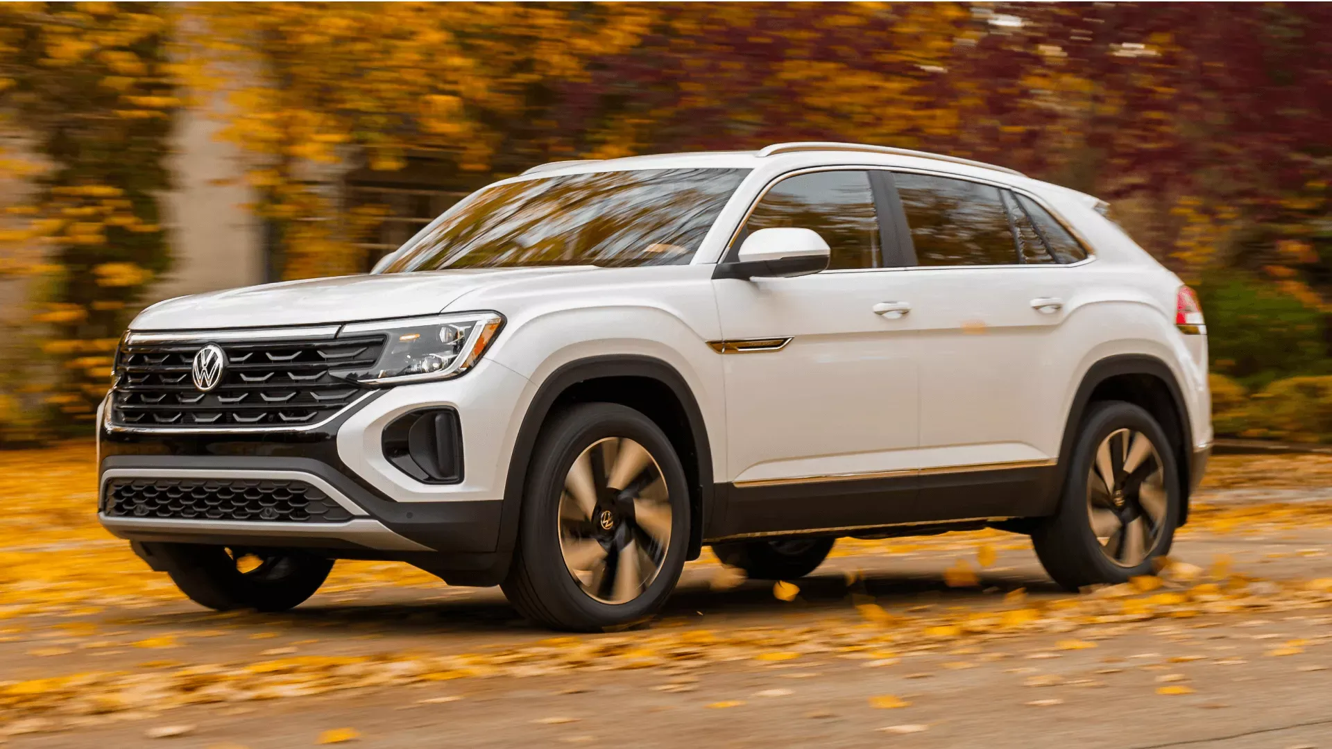 Volkswagen Atlas Cross Sport 2026 blanc en conduite sur route automnale.