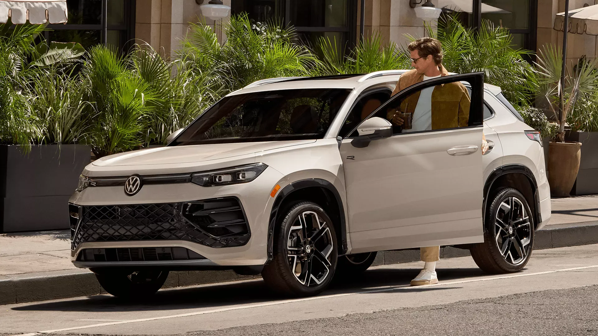 White Volkswagen Tiguan parked in the city with a man near the open door.