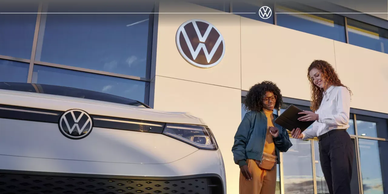 Volkswagen advisor presenting an electric vehicle to explain monthly insurance costs.