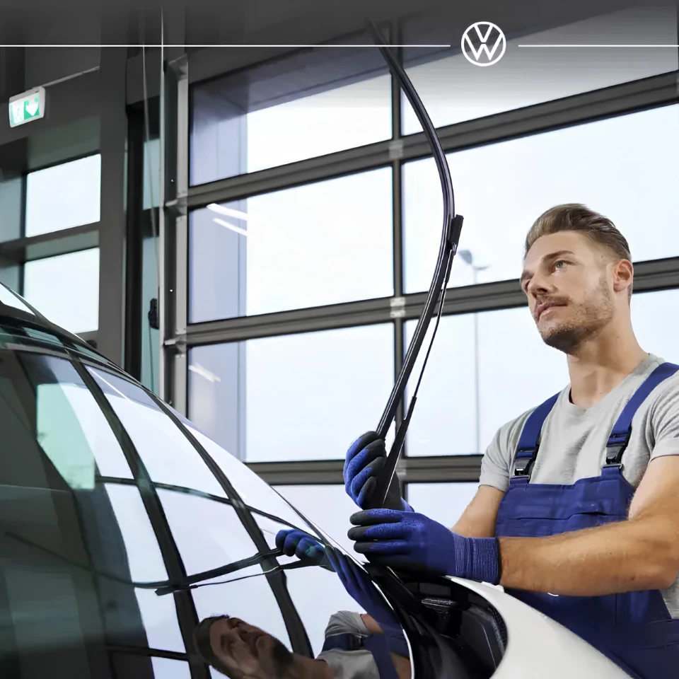 Technicien Volkswagen vérifiant un essuie-glace dans le cadre de l’entretien mensuel et annuel d’une voiture.