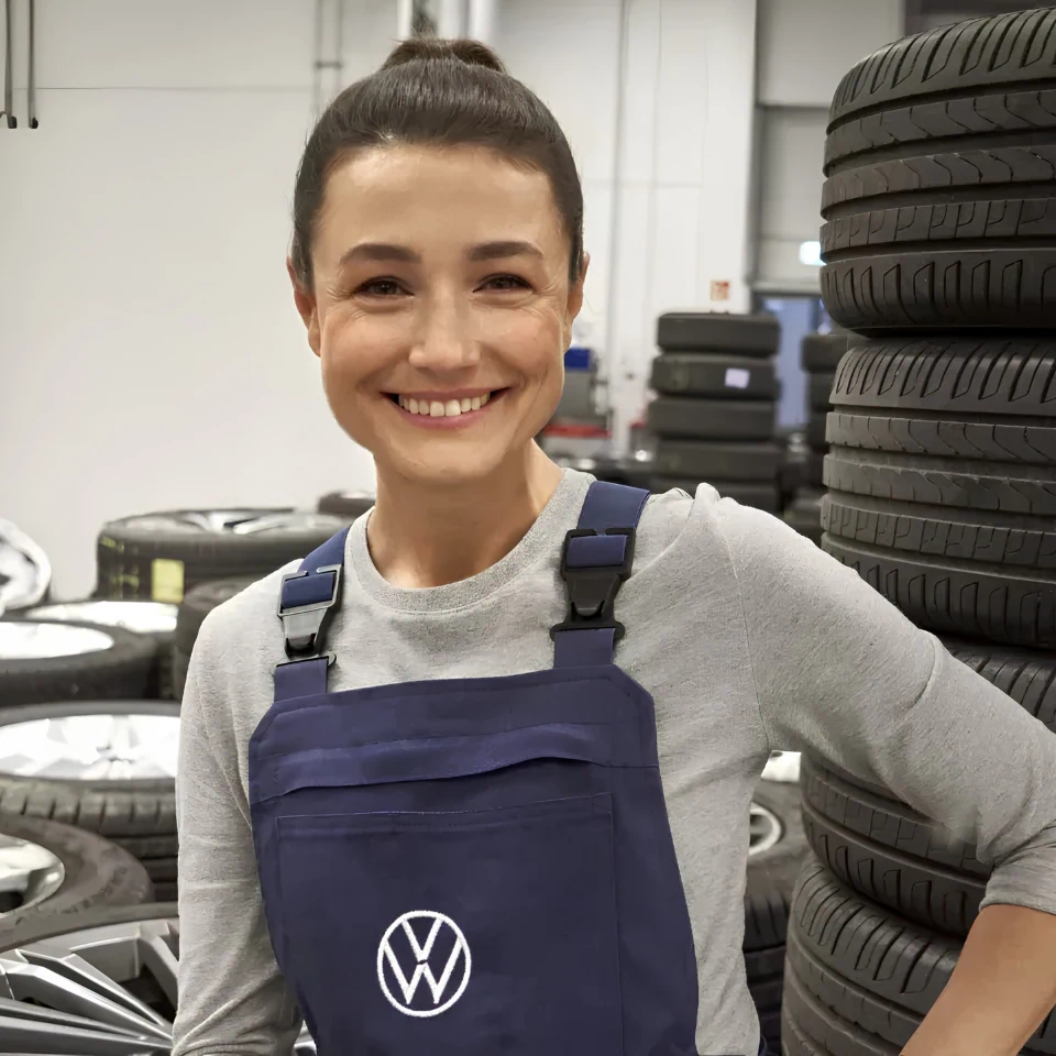 Technicienne Volkswagen près de pneus pour illustrer les étapes essentielles d’entretien d’une voiture.