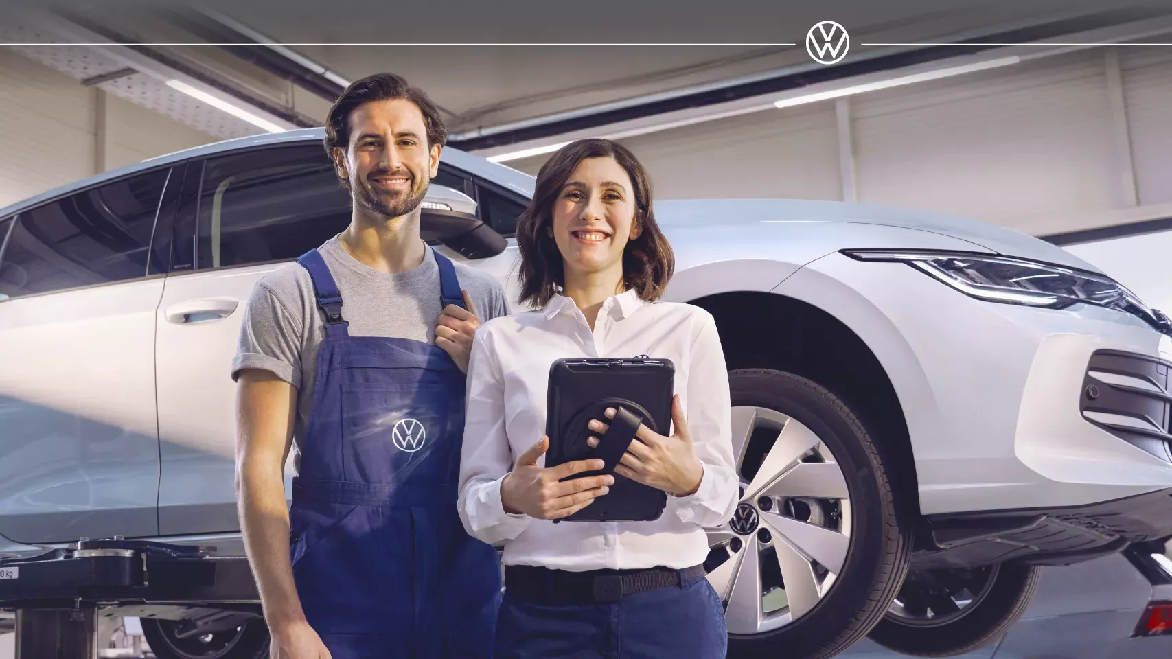 Technicien et conseillère Volkswagen en atelier pour prolonger la durée de vie d’une voiture.
