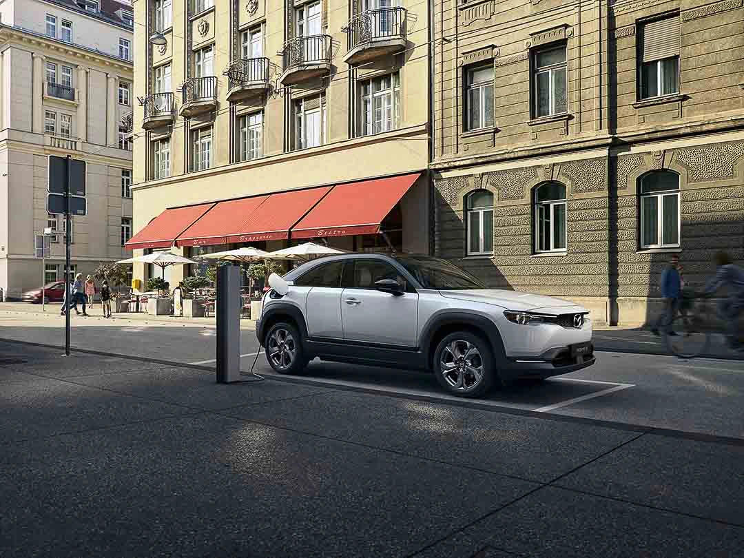 Mazda MX-30 &eacute;lectrique stationn&eacute; en ville comme choix de voiture &eacute;lectrique abordable.