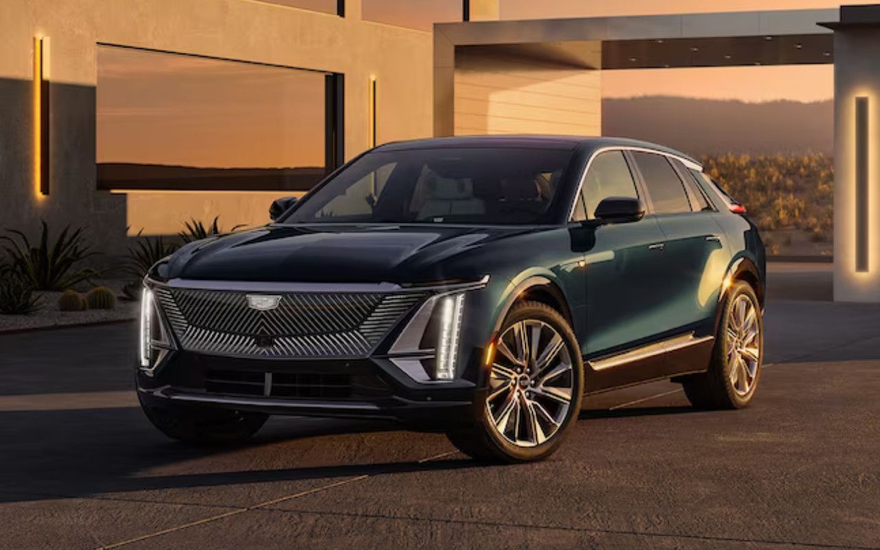 vue latérale avant d'une Cadillac Lyriq 2024 près d'une maison moderne