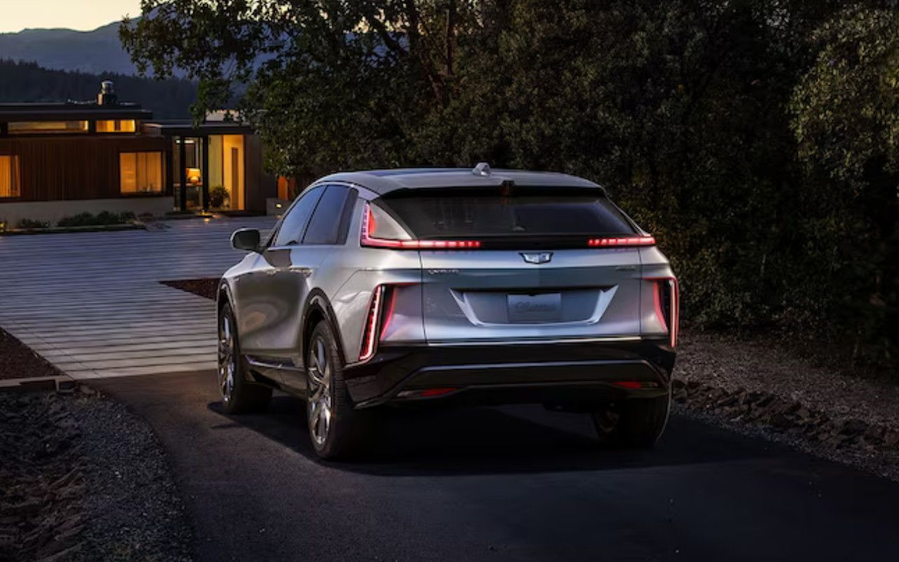 vue latérale arrière d'une Cadillac Lyriq 2024 dans une entrée de maison en fin de soirée