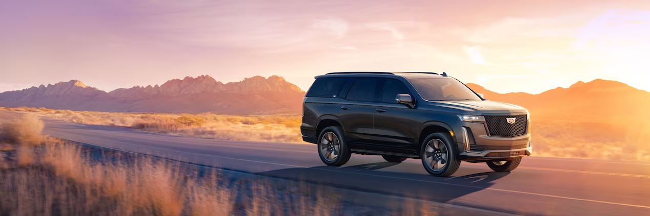 vue latérale avant d'un Cadillac Escalade ESV 2023 sur une route au crépuscule 