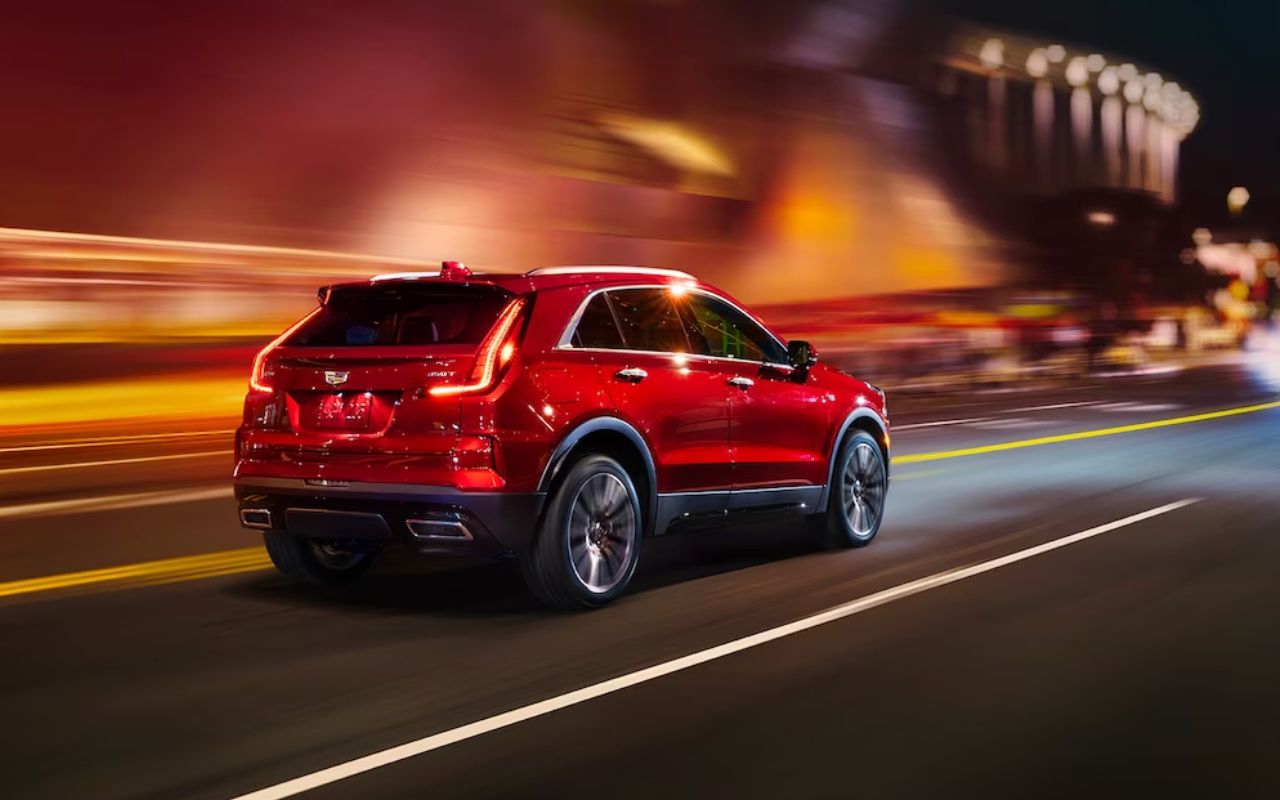 vue latérale arrière d'une Cadillac XT4 2024 sur une route en ville, le soir