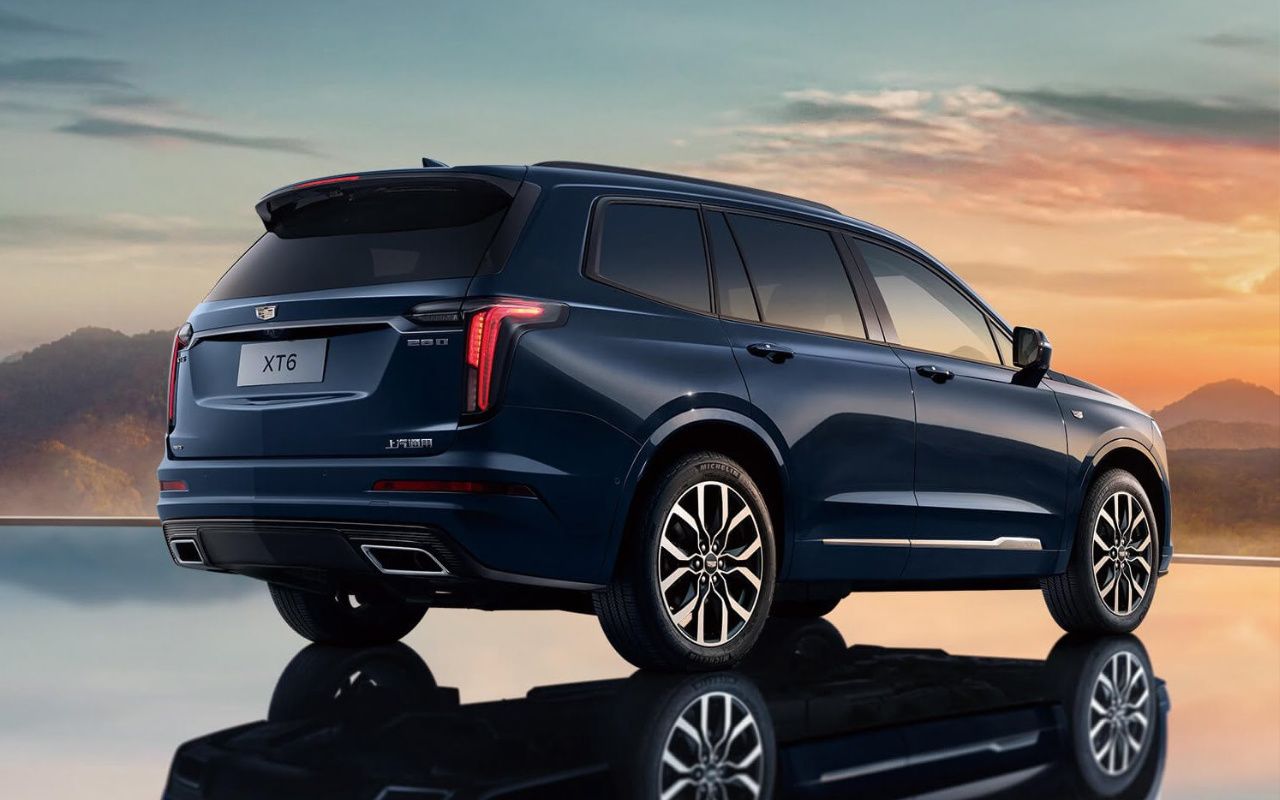 vue latérale arrière d'une Cadillac XT6 2024 sur une surface miroir au crépuscule