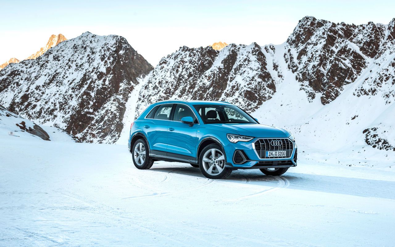 vue latérale avant d'une Audi Q23 2023 sur une montagne enneigée