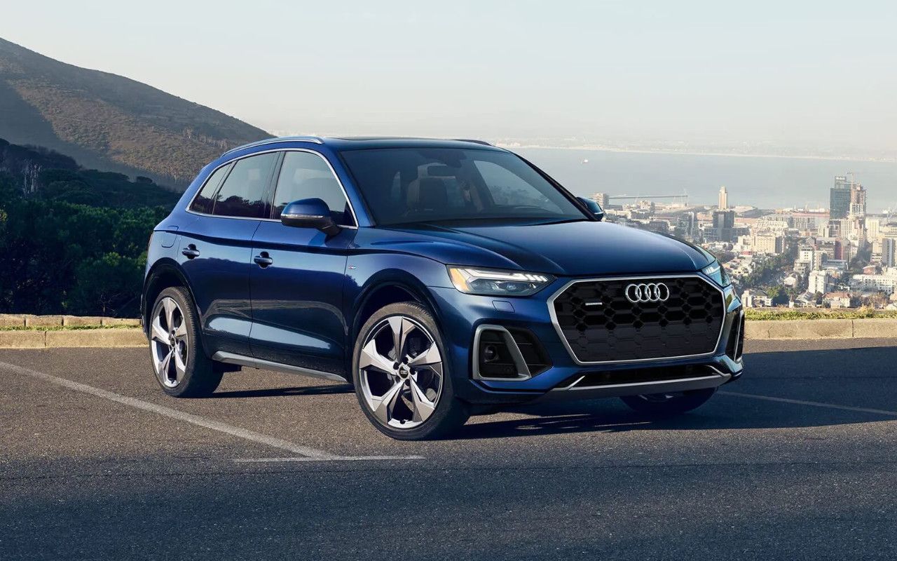 vue latérale avant d'une Audi Q5 2023 dans un stationnement en montagne surplombant une ville
