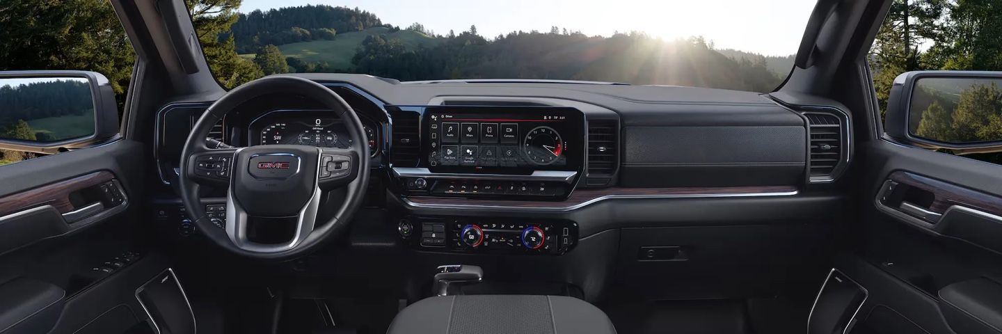 Intérieur du GMC Sierra 1500 2026 avec tableau de bord numérique et volant multifonction, mettant en valeur le confort et la technologie embarquée.