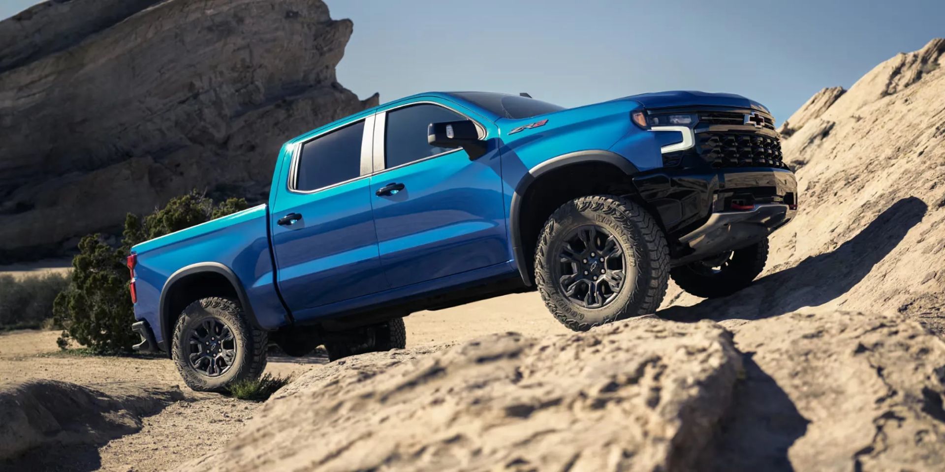 Chevrolet Silverado 1500 2026 bleu grimpant une pente rocheuse dans un désert ensoleillé, mettant en valeur sa traction et ses capacités hors route.