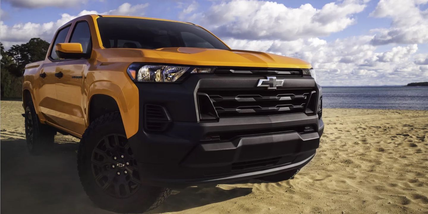 Chevrolet Colorado 2026 jaune garé sur la plage avec ciel partiellement nuageux en arrière-plan.