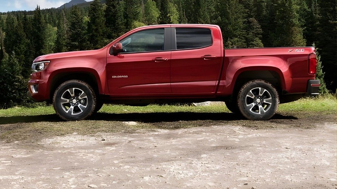 Chevrolet Colorado rouge 2015 stationn&eacute; en nature, illustrant un camion usag&eacute; robuste et polyvalent.