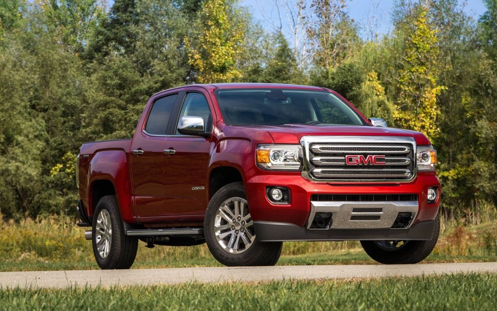 GMC Canyon rouge entre 2015 et 2022 gar&eacute; sur une route de campagne, parfait exemple de camion usag&eacute; fiable.