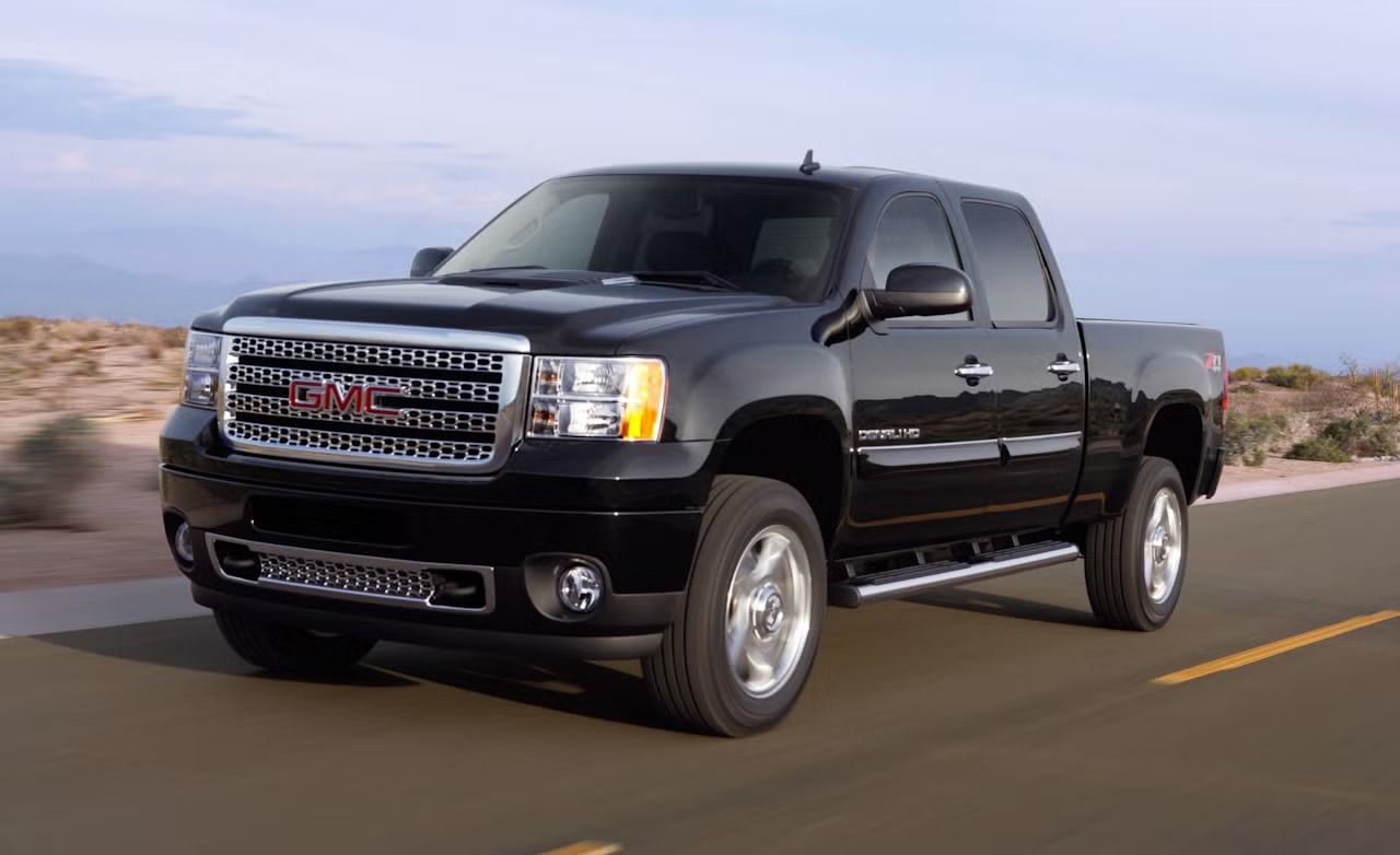 GMC Sierra HD 2011 Denali noir roulant sur une route d&eacute;sertique, d&eacute;montrant la durabilit&eacute; des mod&egrave;les HD.