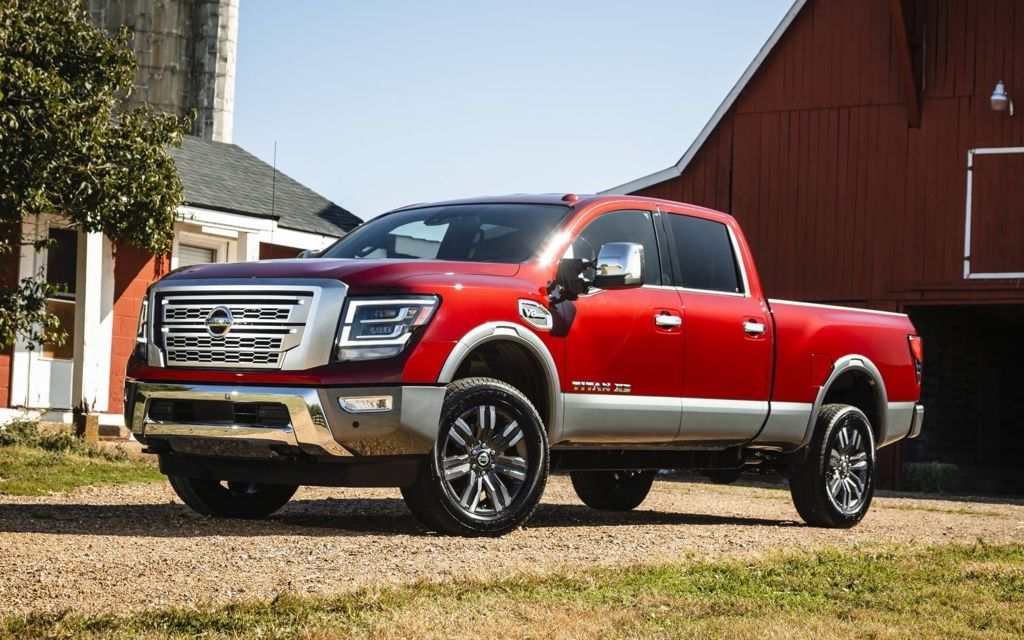 Nissan Titan 2020 rouge gar&eacute; devant une grange, illustrant un camion usag&eacute; puissant et bien entretenu.