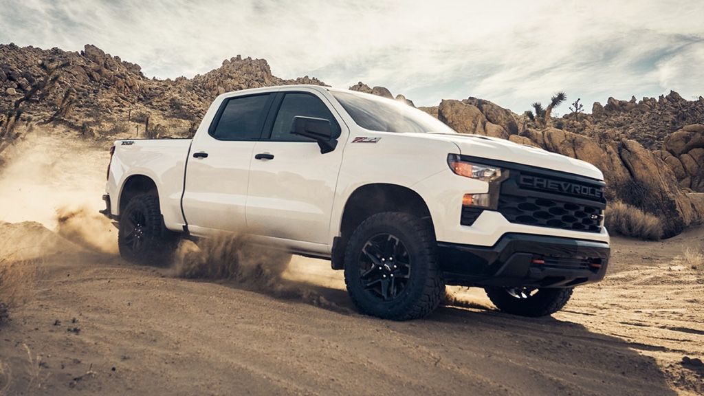 Chevrolet Silverado 1500 2025 blanc roulant dans le d&eacute;sert, d&eacute;montrant ses capacit&eacute;s tout-terrain et sa puissance.
