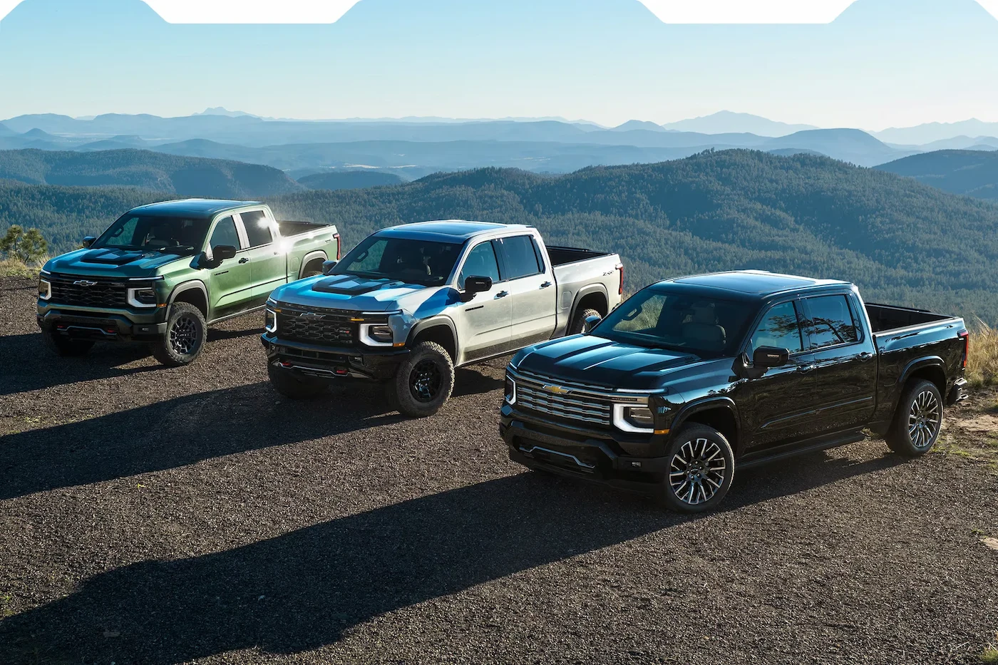 Trois versions du Chevrolet Silverado 1500 2027 devant un paysage montagneux.