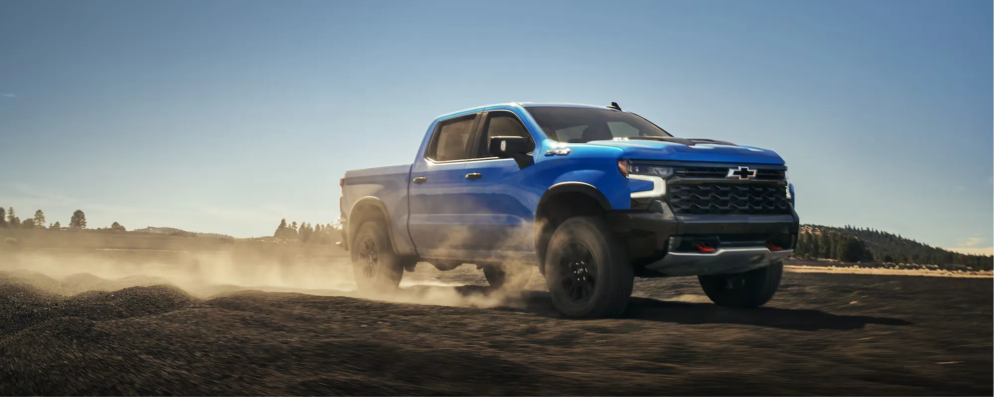Chevrolet Silverado 1500 2026 bleu roulant sur un terrain de gravier.