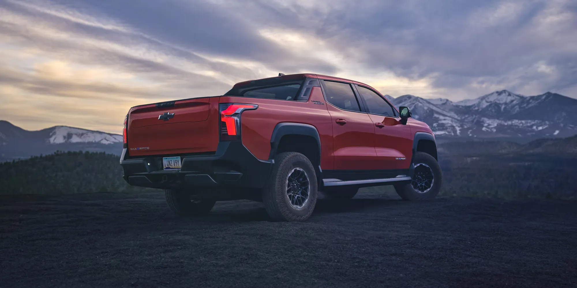 Chevrolet Silverado EV 2026 rouge vu de l&rsquo;arri&egrave;re devant des montagnes.