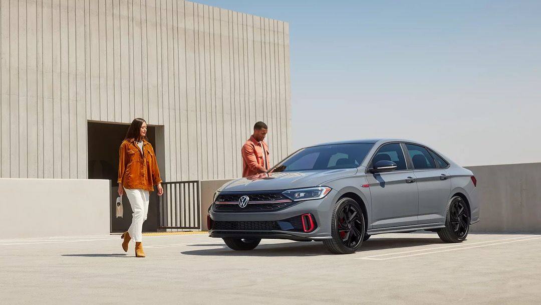 Man and a woman heading to the 2023 VW Jetta GLI.