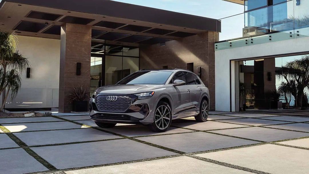 Front 3/4 view of the Audi Q4 e-tron parked in front of a house.