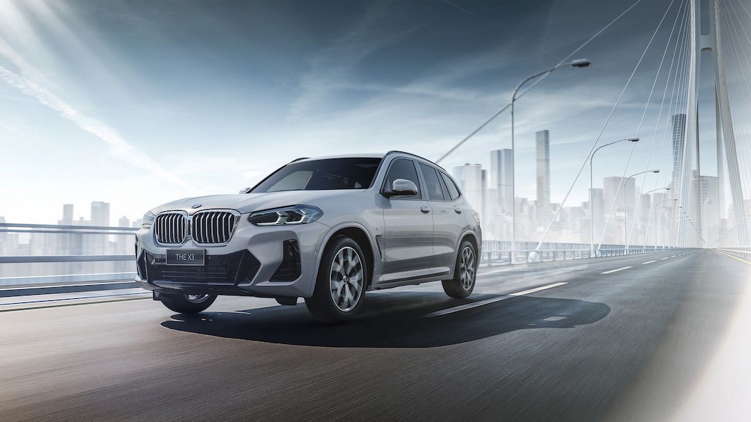Front 3/4 view of the 2023 BMW X3 being driven on a bridge.
