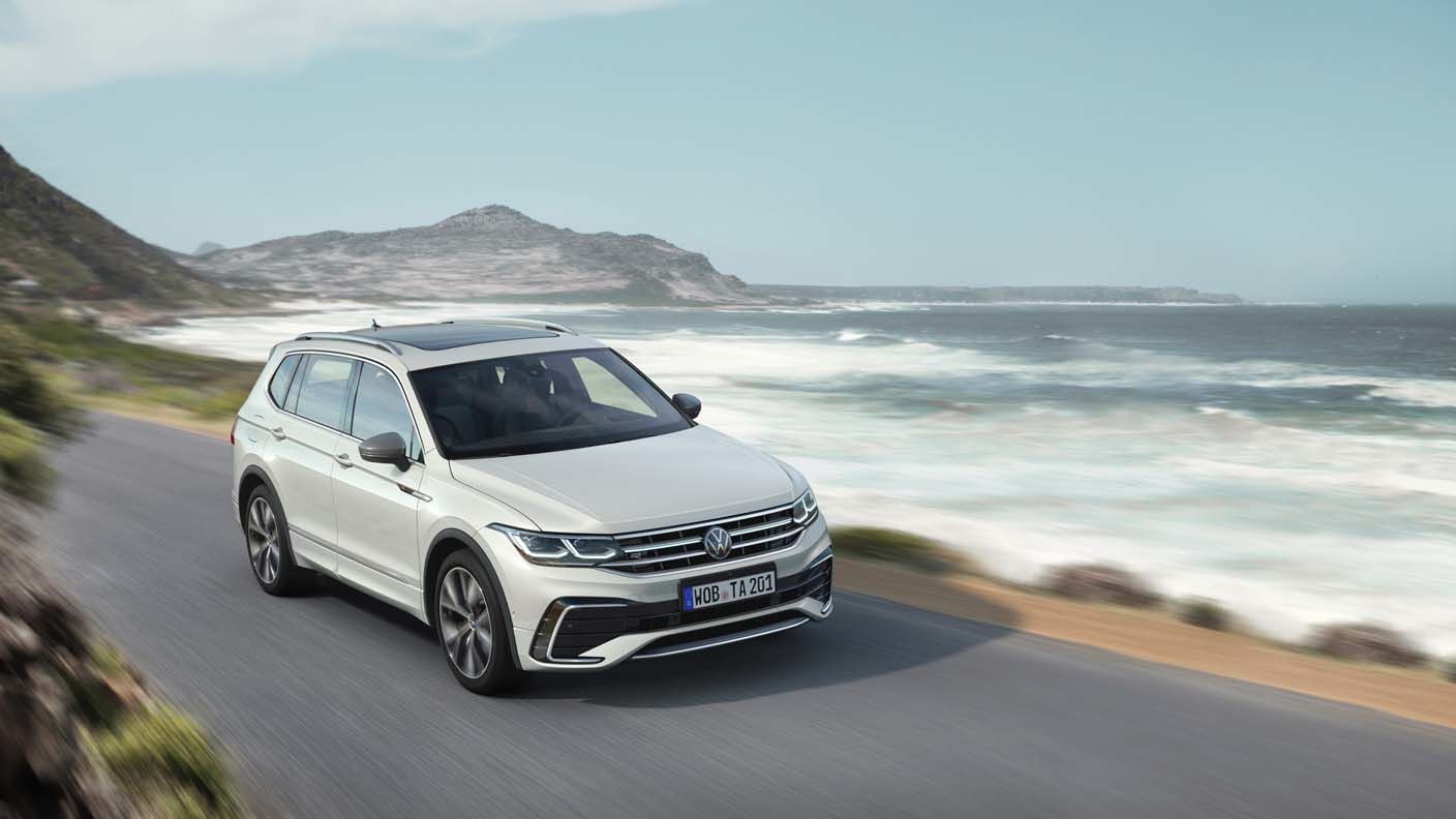 Vue 3/4 avant du Volkswagen Tiguan 2023 roulant sur une route au bord d'une mer.