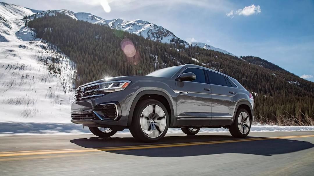 1/4 front and 3/4 side view of the 2023 Volkswagen Atlas Cross Sport SUV driving on a road.