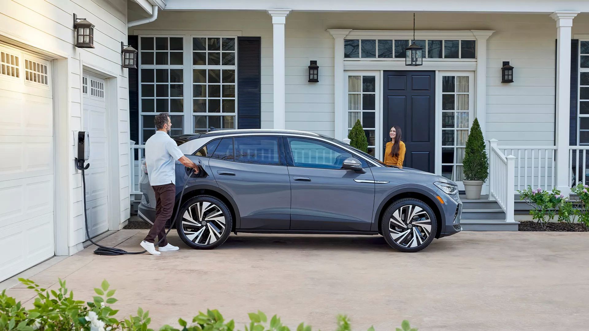 Un père de Famille qui branche son Volkswagen ID.4 2024 stationné dans son allée.