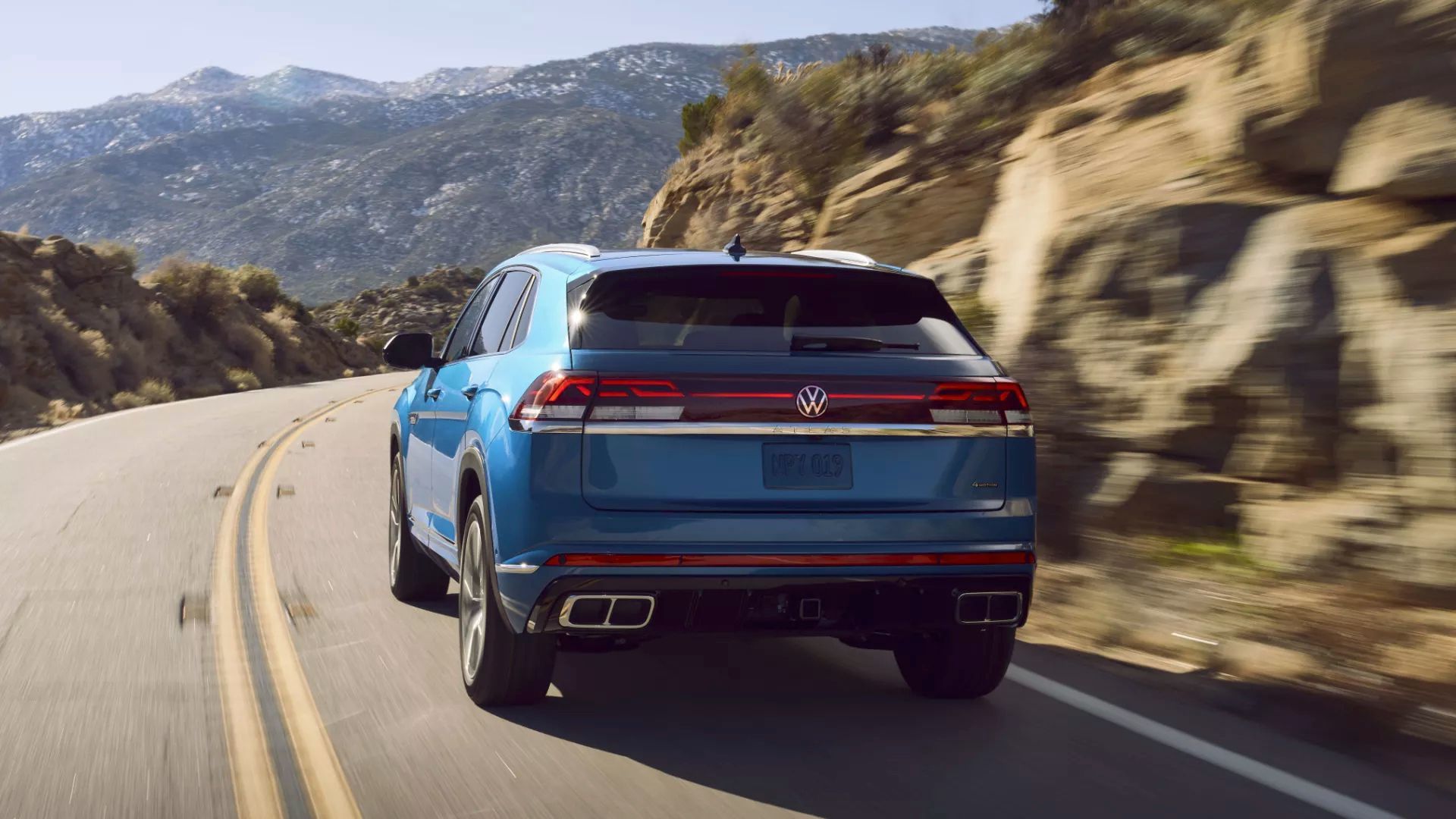 Vue arrière du Volkswagen Atlas Cross Sport 2024 qui roule sur une route de montagne.