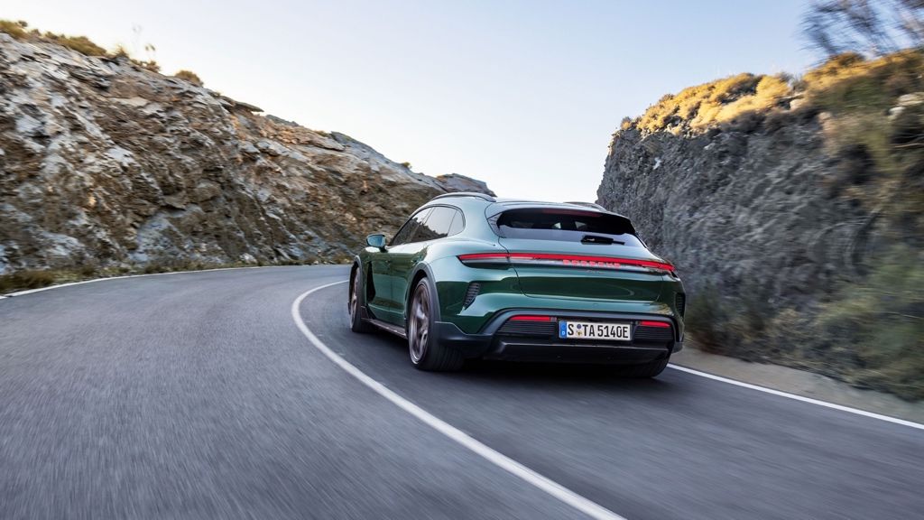 Rear 3/4 view of the 2025 Porsche Taycan driving on a road.