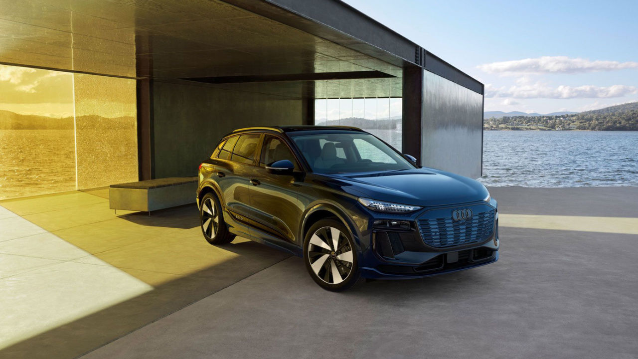 vue latérale avant d'une Audi Q6 e-tron 2025 devant une maison moderne