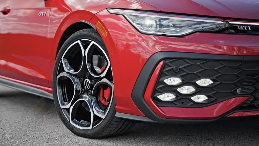 Gros plan sur la roue avant et le pare-chocs de la Volkswagen Golf GTI 2026 rouge, mettant en valeur son design sportif et les détails esthétiques qui ont contribué à son titre MotorTrend 2026.