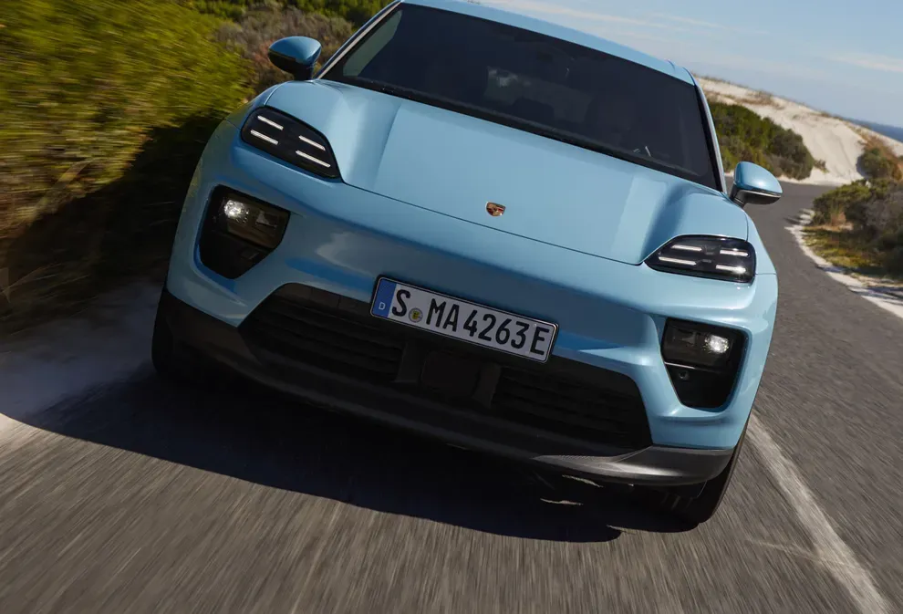 Blue 2026 electric Porsche Macan on the road to illustrate range and electric-model performance.