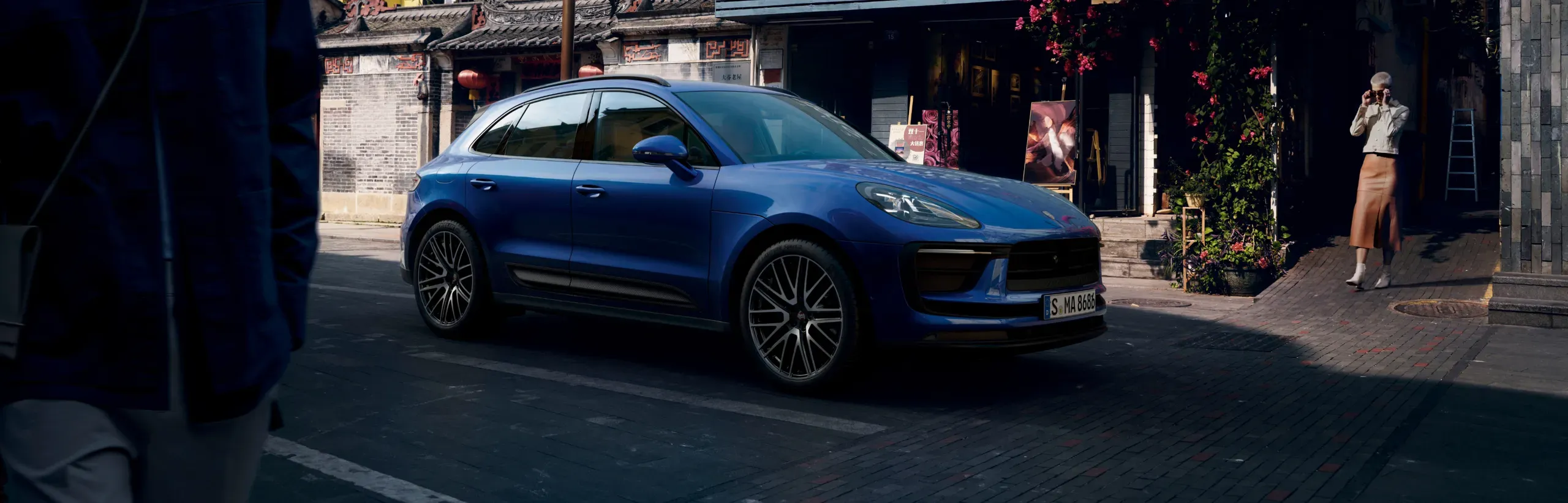 Blue 2026 gas Porsche Macan seen outdoors to illustrate Porsche SUV pricing and trims.