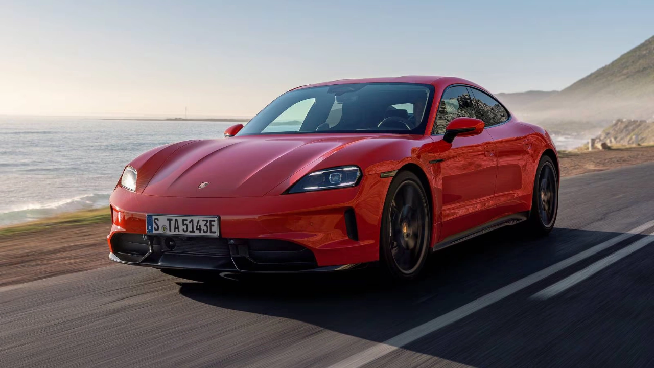 Front three-quarter view of the electric Porsche Taycan sedan driving on a scenic road