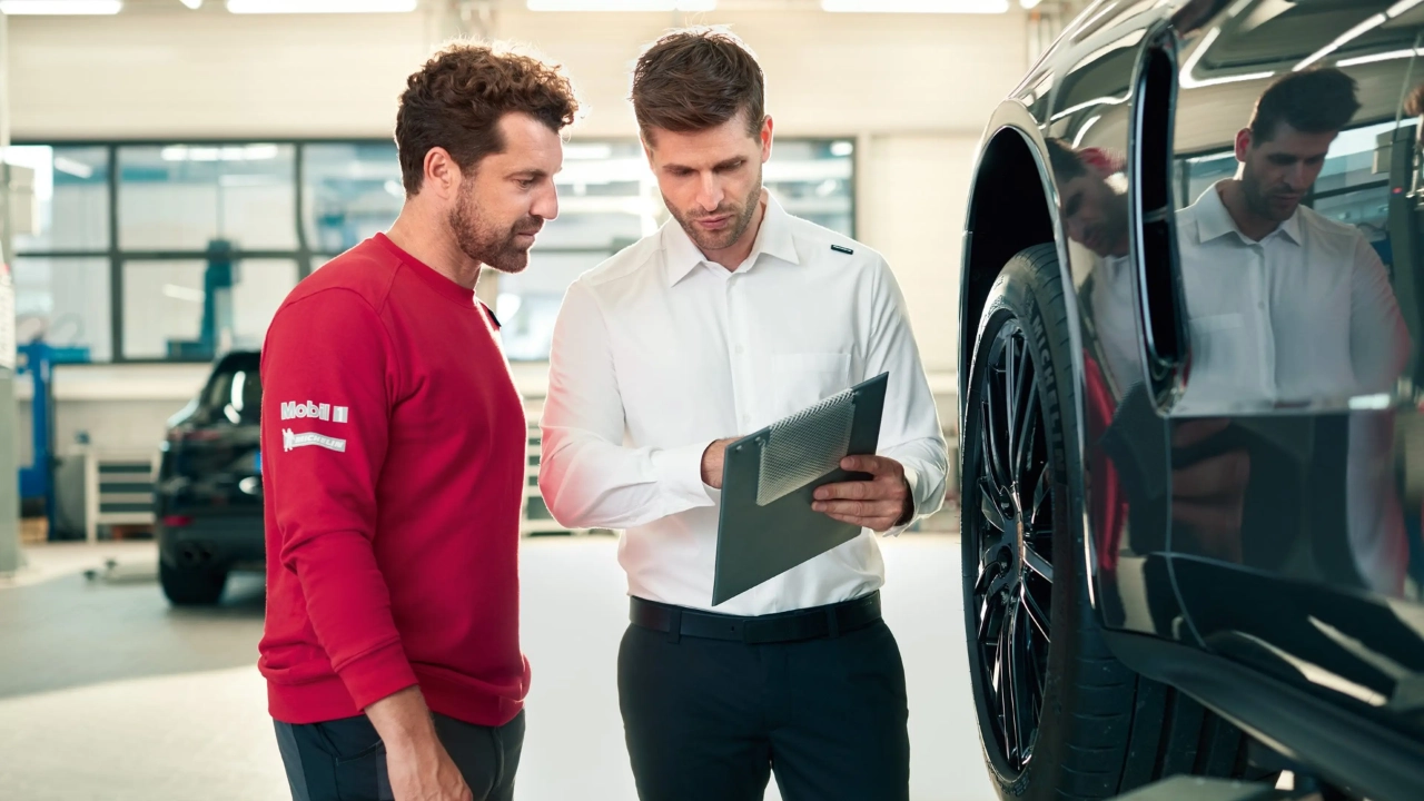 Porsche service technician inspecting the mechanical components of a vehicle