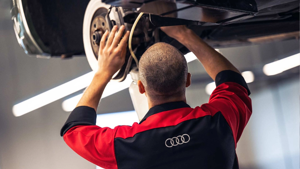 Technicien expert effectuant une inspection détaillée du système de freinage d'un véhicule Audi
