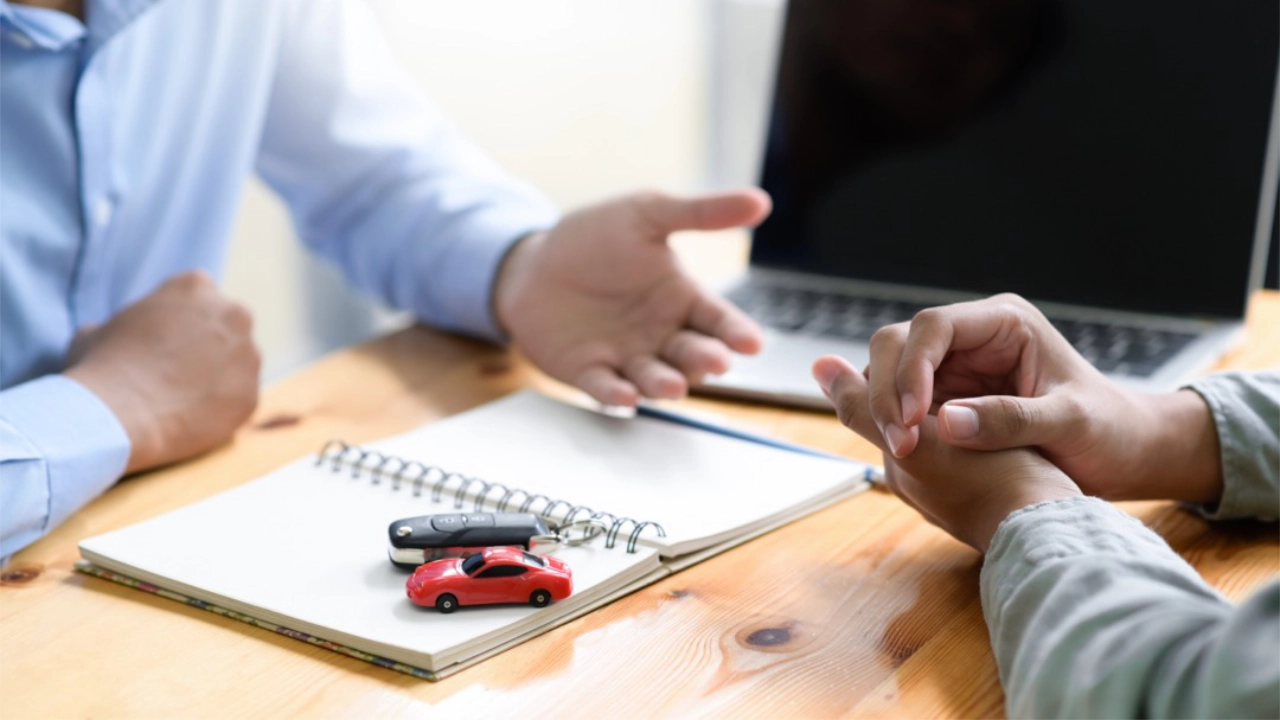 Someone reviewing a vehicle purchase or financing agreement on a desk