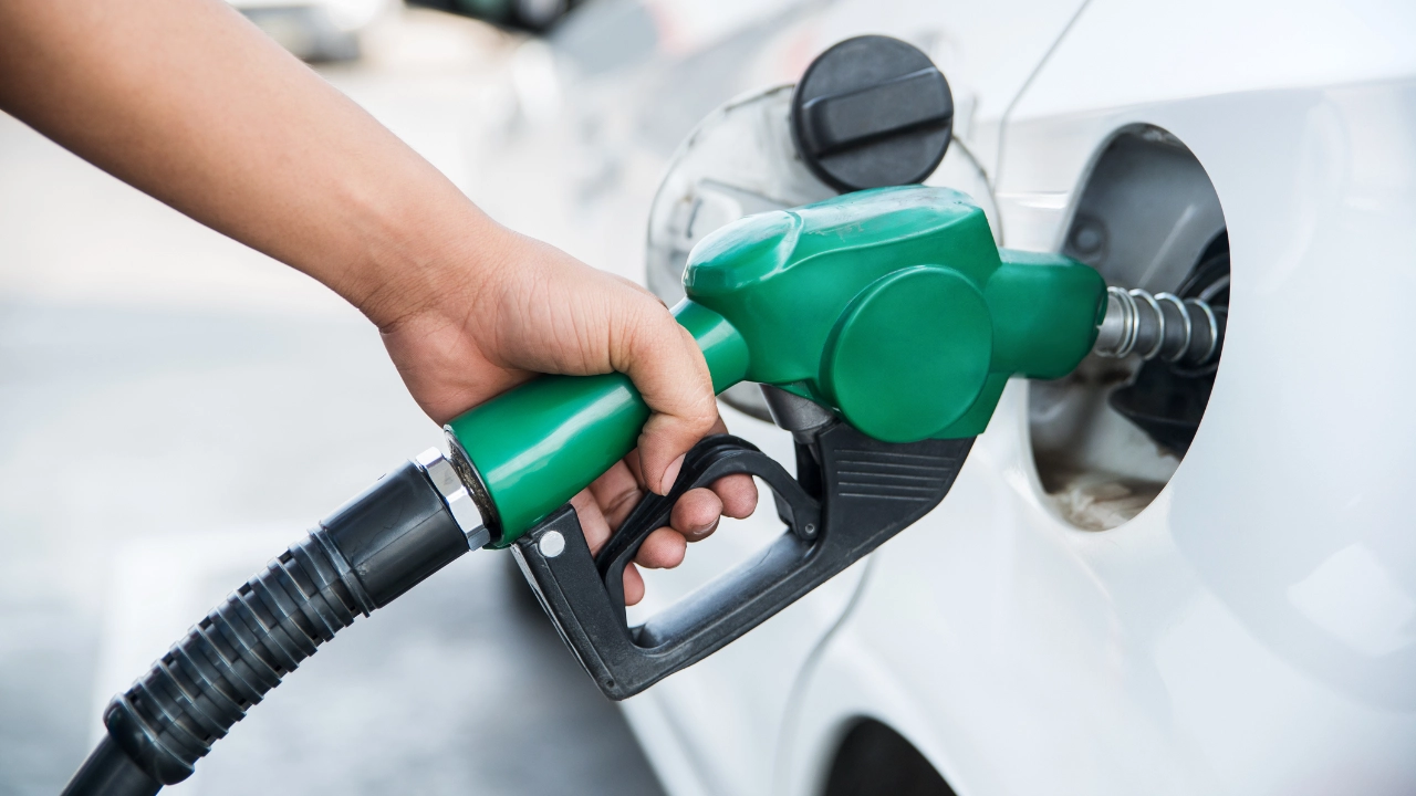 Hand inserting a gas pump nozzle into a car fuel tank