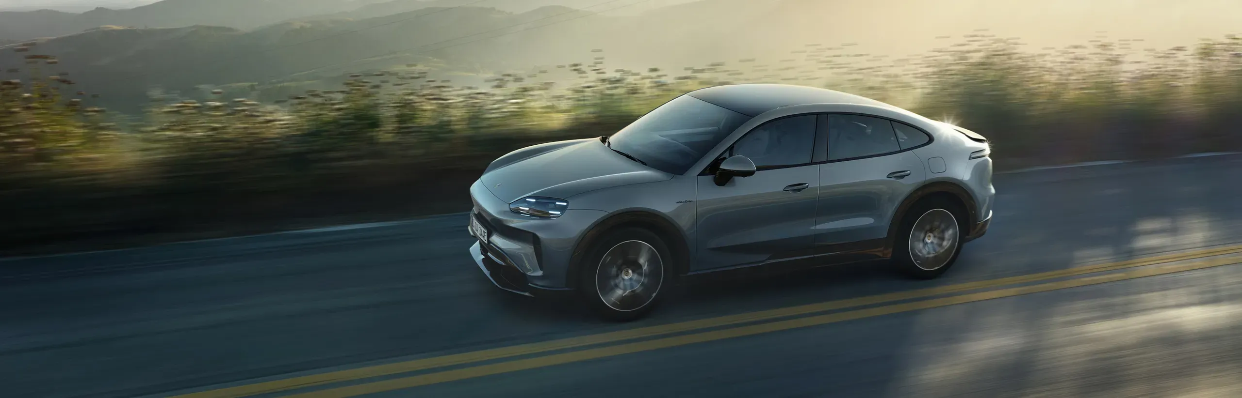 2027 Porsche Cayenne electric coupe driving on a road, highlighting its sloping roofline.