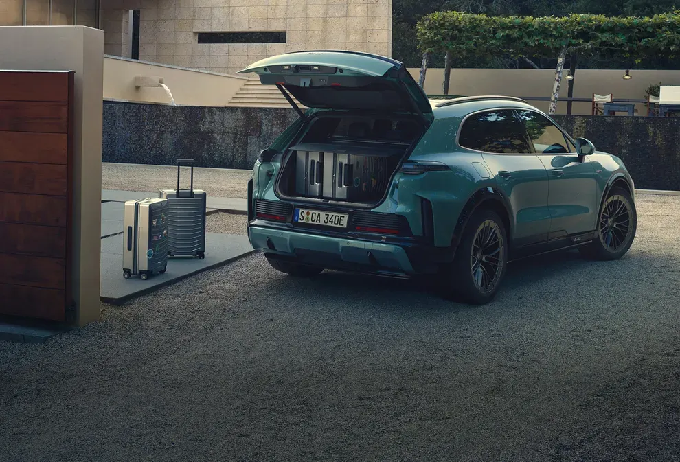 Open cargo area of the 2027 Porsche Cayenne electric SUV with suitcases inside the trunk.