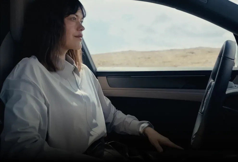 Driver seated behind the wheel inside a 2027 Porsche Cayenne electric SUV.